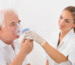 A healthcare professional assisting an elderly patient with cystic fibrosis using a nebulizer