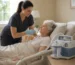 A woman in a hospital bed with a suction machine nearby, indicating she is undergoing treatment