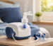 Modern nebulizer machine on a bedside table with visible mist, medicine cup, tubing, and face mask in a softly lit home bedroom setting